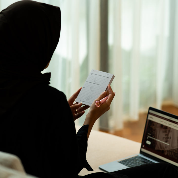 Une femme lit une carte Qalbeen devant son ordinateur