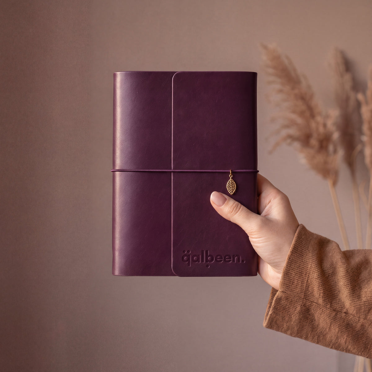 Carnet organisateur L'Archive Deep Plum, prune profond, charm feuille, tenu à la main